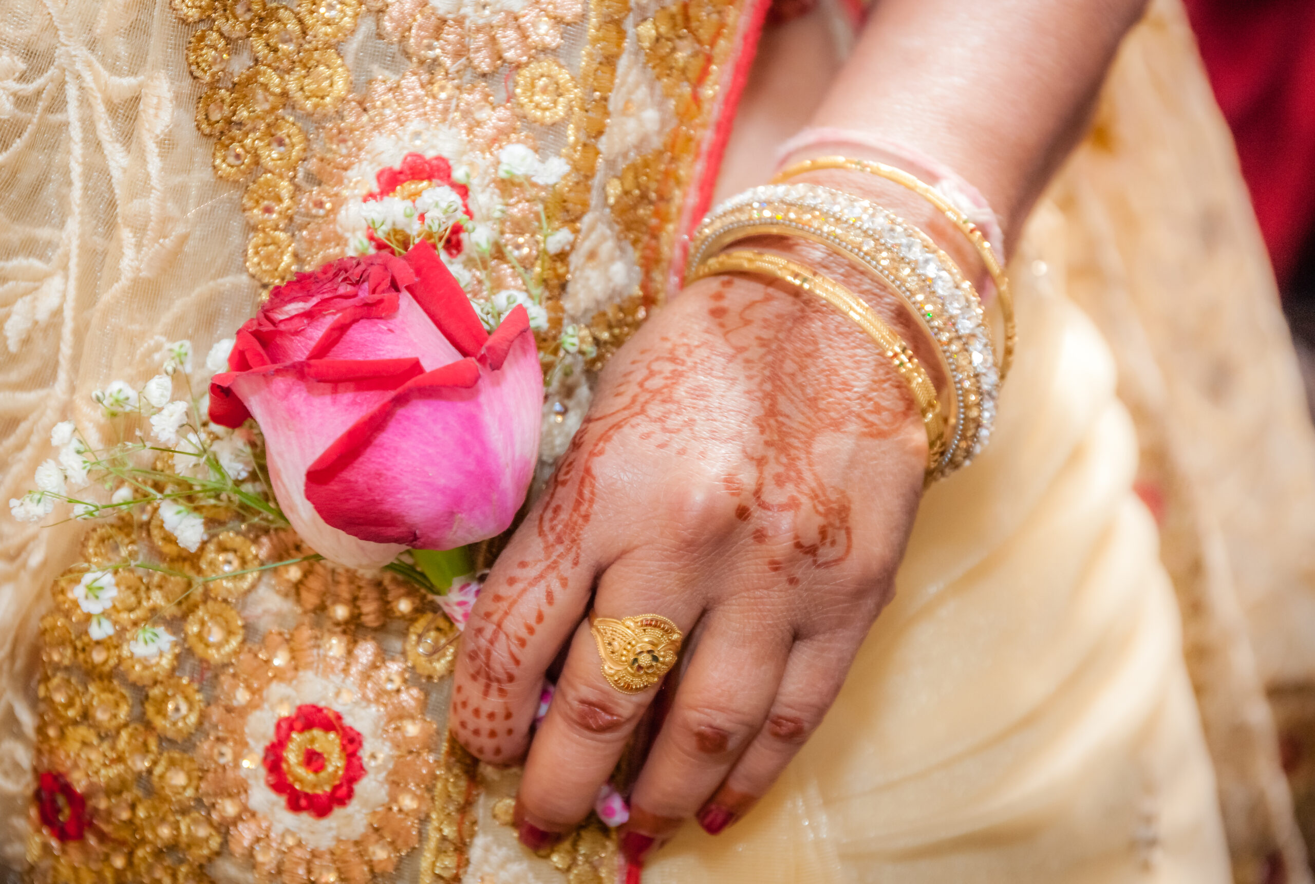 Indian bride hand painted with henna tattoo, holding a red rose
