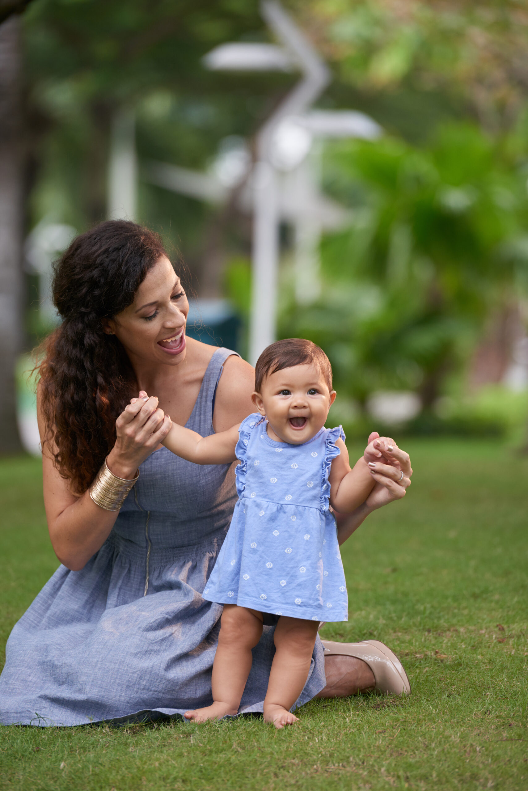 Cheerful mother playing with her adorable little daughter in park