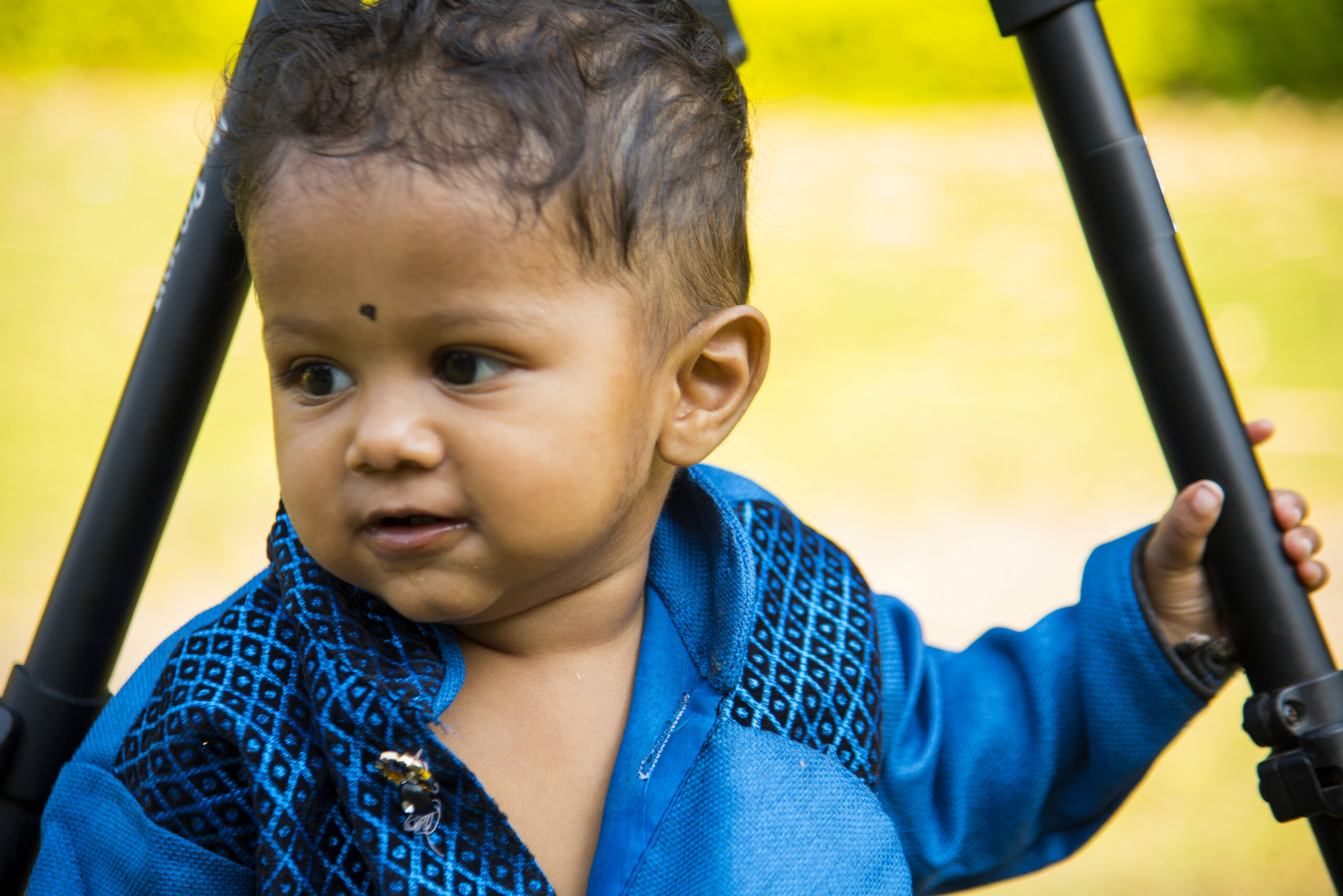 Cute one year old Indian boy plays happily in garden.