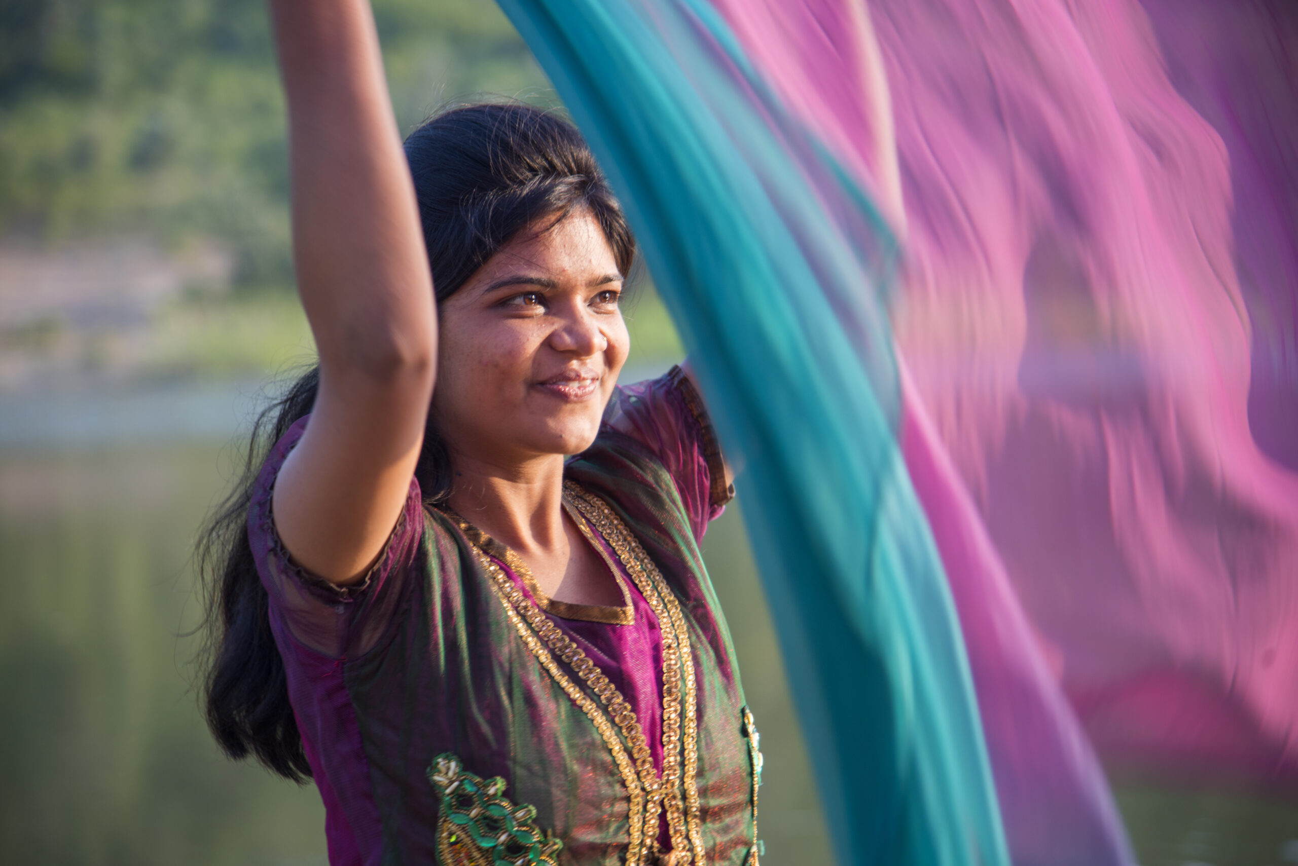 Young happy Indian girl playing with her pink scarf at outdoor.